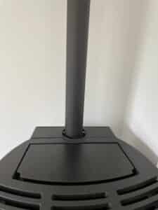 Gros plan sur la base noire d'un poêle ou radiateur à colonne, montrant la sortie verticale du tuyau d'évacuation ou de chauffage.