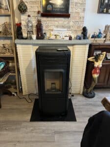 Poêle à granulés noir devant une cheminée en briques, avec un panneau "Bière culte depuis 1240" et une statue de pin-up rouge.