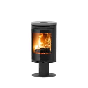 Poêle à bois cylindrique noir design avec un plateau en pierre ollaire gris. Le foyer en fonte présente des flammes vives derrière la vitre courbe.