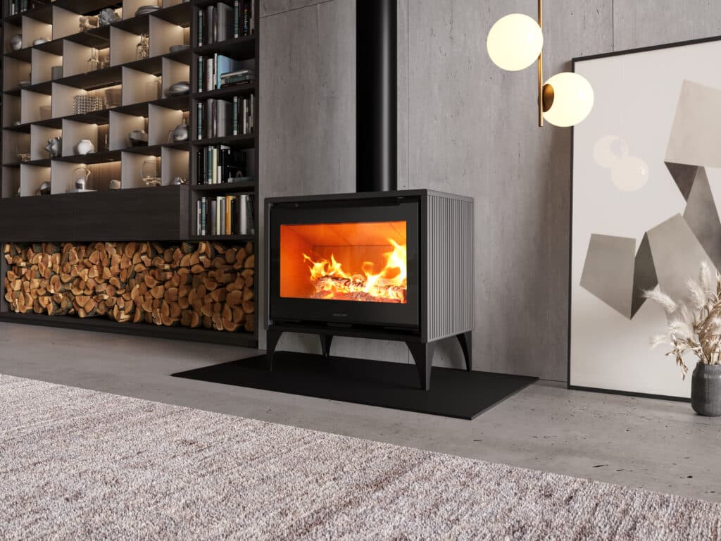 Intérieur moderne : poêle à bois Jolly Mec devant un mur en béton, feu ardent. Grand bûcher intégré et bibliothèque minimaliste éclairée.