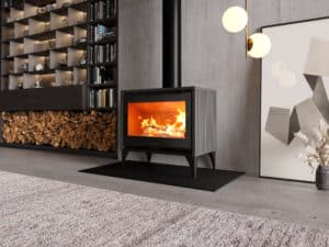 Intérieur moderne : poêle à bois Jolly Mec devant un mur en béton, feu ardent. Grand bûcher intégré et bibliothèque minimaliste éclairée.