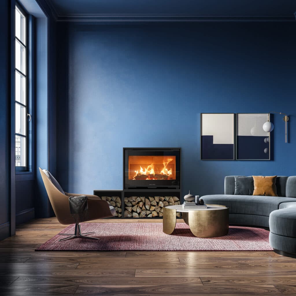 Cheminée moderne intégrée avec bûches apparentes dans un salon au mur bleu profond. Canapé incurvé, fauteuil design et table basse or.