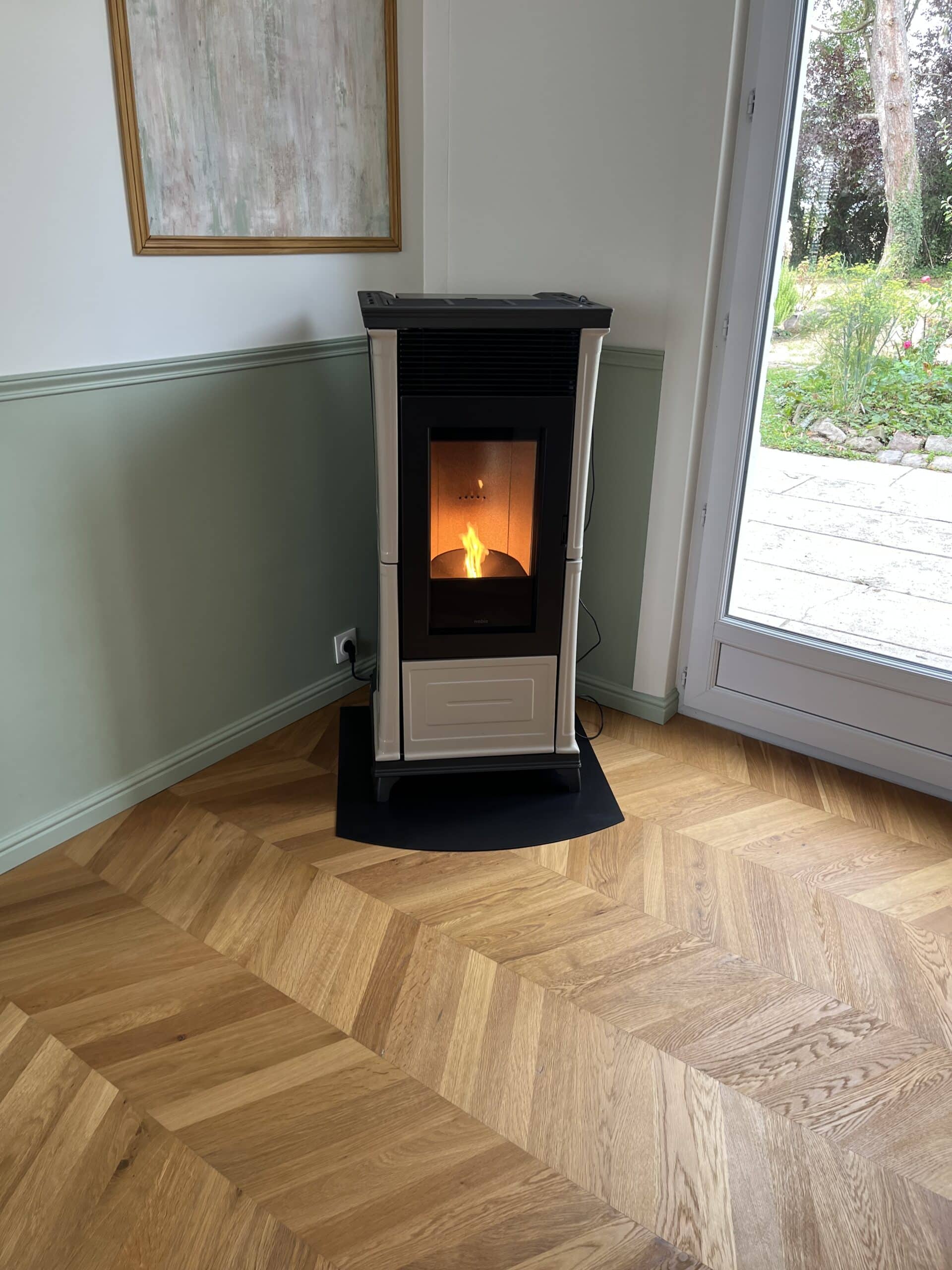 Poêle à granulés moderne Nobis sur parquet chevrons Poêle Nobis allumé sur parquet en chevrons, intérieur moderne et chaleureux.